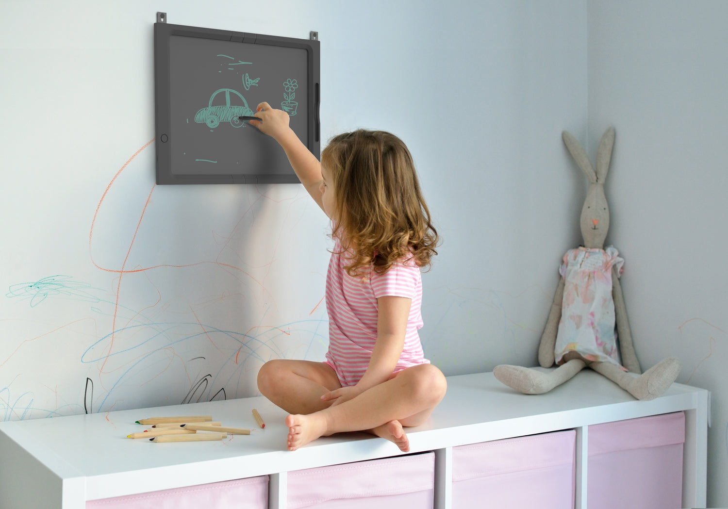 Child drawing on extra‑large 21 inch LCD digital board next to whimsical bunny rabbit toy and colored pencils