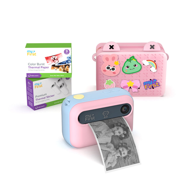 myFirst Insta 20 pink and blue instant print camera for kids printing a photo, shown with a carrying bag, Color Burst thermal paper, and sticker rolls.