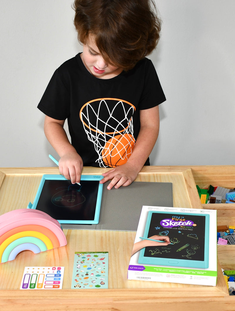 A boy is drawing with a drawing pad for kids.