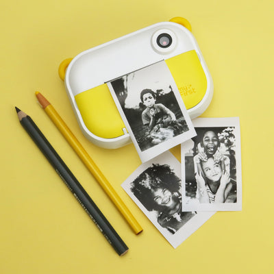 "myFirst instant print camera for kids using thermal printing to create black-and-white photos; child-friendly design with sample prints and pencils on a yellow background.