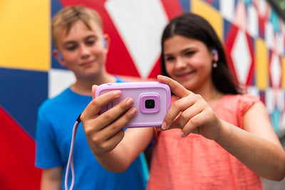 Preteens using purple pink kids video camera to take selfie, demonstrating myFirst Camera 50 for creative photography and safe social sharing